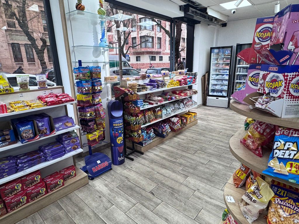 Fachada iluminada del estanco 24 horas en la Avenida de Miraflores, Sevilla, abierta de noche para atender a vecinos y clientes urgentes.